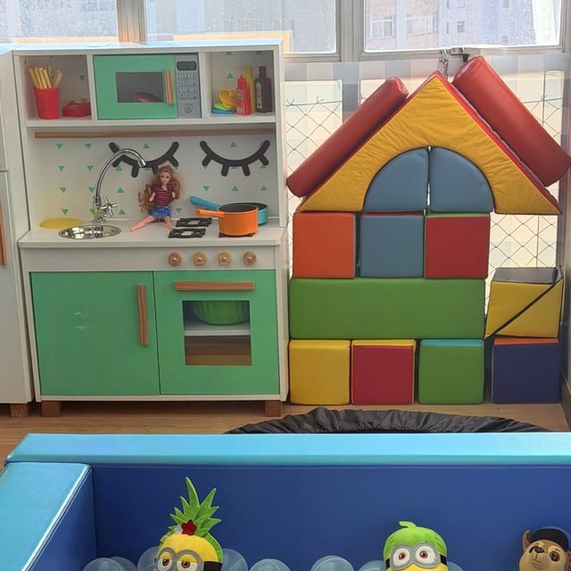 Cozinha de brinquedo, casinha de blocos de espuma e cama elástica na sala de atendimento