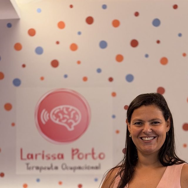 Larissa Porto na recepção do consultório, ao lado do painel da marca